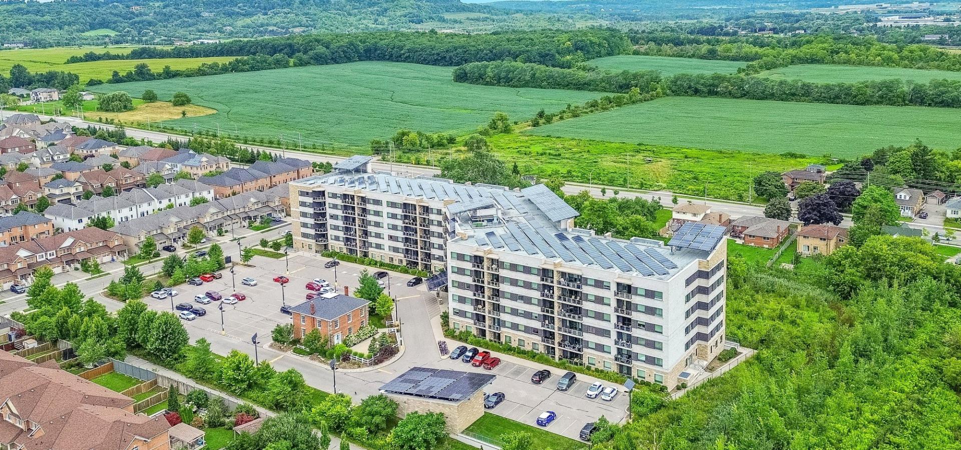Condo Apartment building with solar panels surrounded by green space with escarpment views