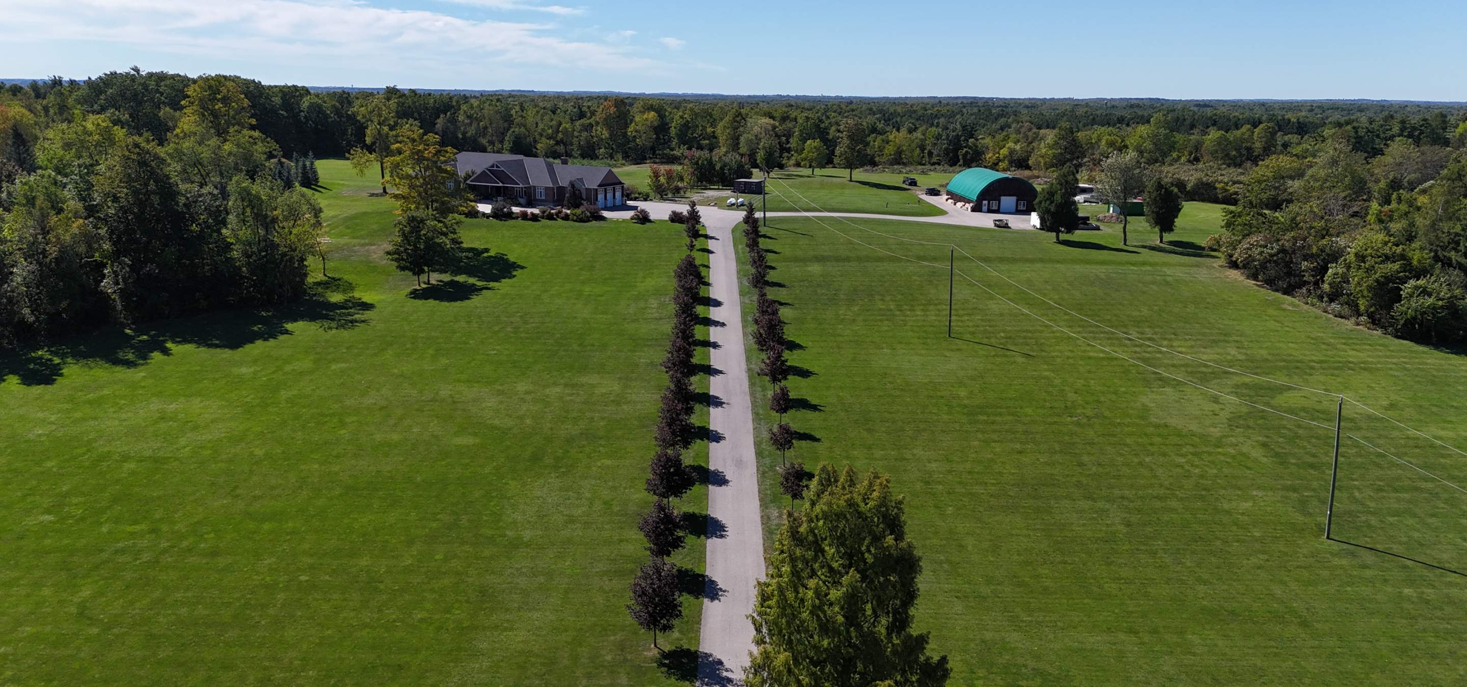 Long tree lined driveway leading to beautiful bungalow and large barn