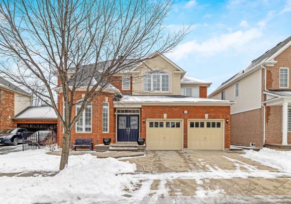Elegant brick home with double garage in a snowy setting.