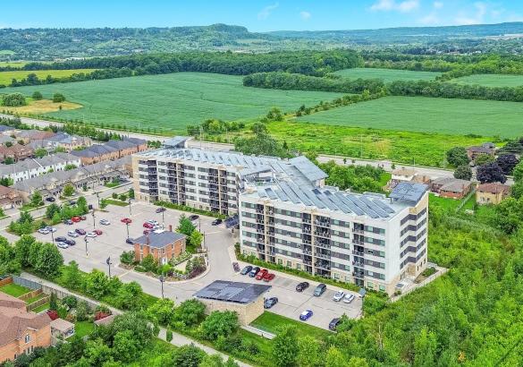 Condo Apartment building with solar panels surrounded by green space with escarpment views